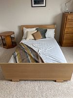 Frontal view of the bed frame showing the headboard and footboard with mattress and pillows for scale.