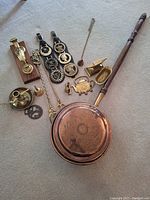 Full lot showing all items: copper bed warmer, door knockers, fireplace tools, candle holder, wooden mounted brass door knocker.
