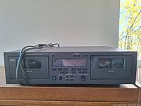 Front view of NAD 616 double cassette deck showing two cassette compartments on sides with control buttons and display window in the center.