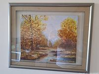 Full frontal photo of the framed oil painting showing the autumnal river landscape.