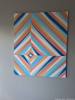 Original abstract geometric striped painting in pastel colors by Marlene Champion hung on beige wall, showing full front face and colors.
