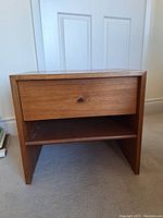 Front view of the solid wood side table showing drawer with knob and open shelf beneath.