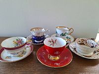 Five porcelain tea cups with matching saucers arranged side by side to show all patterns and details in natural light.