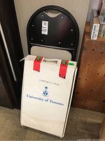 University of Toronto white box labeled for directors chair, with folded black metal chair visible behind