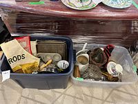 Overview of two plastic bins filled with vintage kitchenware including bakeware, serving utensils, and various kitchen items wrapped in plastic.