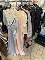 Overview of ladies' clothing hanging on rack, showing sleeping dresses and other garments.