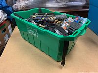 Green bin filled with assorted LEGO pieces including vehicle parts and baseplates