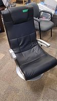 Front angle view of black X Rocker gaming chair showing padded faux leather upholstery, metal arms, and pedestal base.