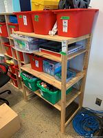 Straight front view showing the whole shelving unit with four shelves. Various items stored on shelves but not included in lot.