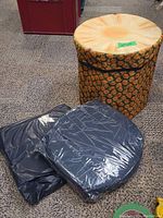 Open pineapple folding storage ottoman with fabric print resembling pineapple texture and color.