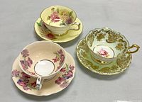 Three teacup and saucer sets arranged on grey surface