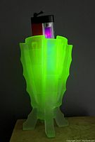 Vase under UV lamp glowing bright green, confirming vaseline/uranium glass