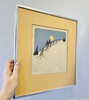 Photo of the framed serigraph held up to show artwork and signature details.