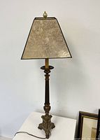 Full view of the Gothic bronzed metal church lamp with mica shade standing on a white surface against a white wall.