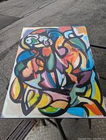 Front view of a large abstract oil painting on canvas with vivid colors and bold black outlines forming fluid shapes.