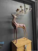 Side view of gold-tone metal reindeer candleholder with six candle cups on antlers.