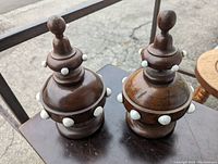Pair of wooden Gothic Victorian finials with beads, placed outside on metal and wooden surfaces