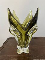 Front angled view of the olive green-hued Chalet Floriform V-33 glass vase showing the floral-shaped top flares and clear glass base with age wear.