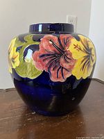 Front and side views of the large cobalt blue ceramic vase with hand-painted red and yellow hibiscus flowers and green leaves.