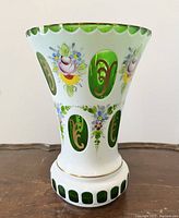 Front view of vase showing emerald green and white flashed glass, hand-painted floral designs, and gilt gold accents.