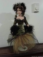 Front view of porcelain doll showing detailed facial features, hair, and dress with feather accents.