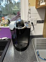 Front view of Keurig coffee maker on kitchen counter showing water reservoir, control buttons, and drip tray.