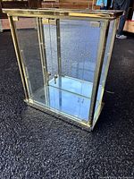 Full front view of brass frame glass display cabinet with mirrored back and locking glass door.