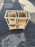 Front view of metal frame storage unit with four wicker drawers showing arrangement and condition.