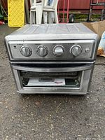 Front view of Black+Decker stainless steel toaster oven showing control knobs and glass door.