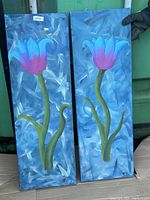 Two vertical paintings showing a flower with blue and pink petals, green stem and leaves on a blue textured background.