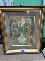 Framed painting showing bouquet of flowers in white vase with brown wood frame and gold accents.