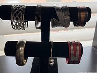 Bracelets arranged on black double rod display stand, showing silver, copper, leather and costume styles
