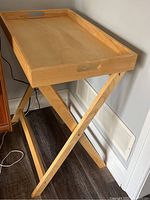 Folding tray table set up showing the tray with raised edges and X-shaped folding legs.