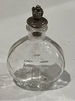 Close-up of the clear glass holy water bottle showing embossed cross and 'HOLY' text, cork, and crown-shaped sprinkler top.