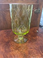 Front view of large green glass vase showing diamond pattern and cylindrical shape with pedestal base