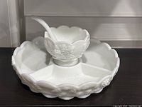Milk glass divided relish tray with small condiment bowl and ladle placed inside center section.