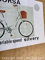 Close-up photo of bicycle box side showing a silver step-in bicycle with a front basket and text indicating variable speed.