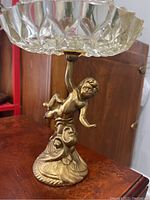 Side view showing the cherub figurine base holding the glass ashtray top