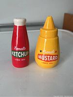 Front view of the vintage ketchup and mustard salt and pepper shakers showing label and colors