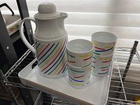 Side angle showing thermal jug with lid and two cups on tray