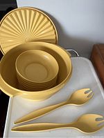 Photo of all items in the vintage Tupperware salad set showing large bowl with lid, six smaller bowls nested inside, and two salad utensils.