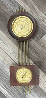 Vintage Westclox wall-mounted barometer and thermometer set on wooden floor, front view.