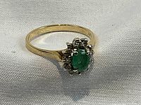 Front view showing oval green emerald center and surrounding diamond halo