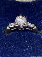 Close-up top view of ring showing central round diamond and tapered baguette side stones