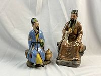 Front view of both blue- and brown-robed figures seated on rock bases