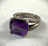 Ring angled front view showing cushion-cut amethyst and Birks hallmark on band interior