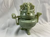 Front view of pale celadon jade incense burner on tripod base with lid in place
