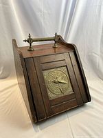 Angled front view of mahogany scuttle showing shape, handle, front plaque