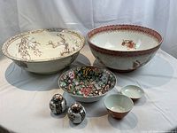 Seven pieces arranged on white drape, two large bowls at rear, medium bowl and two small bowls in front, jars at center