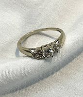 Front angled view of ring showing center diamond and side cluster diamonds